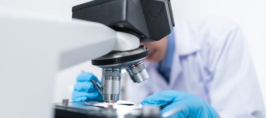 Close-up of a scientist examining samples under a microscope in a lab setting.